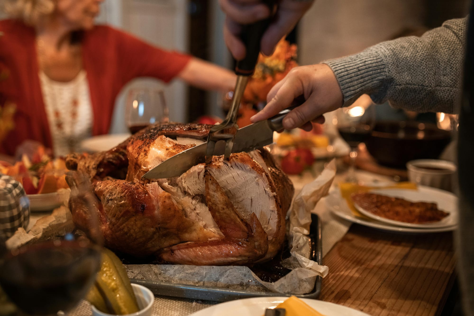 Carving a holiday turkey during a family dinner table gathering.